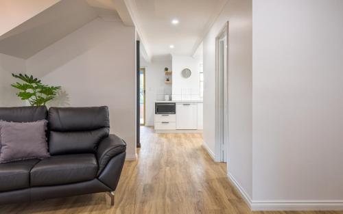 a living room with a black couch and a kitchen at Middleton Beach Holiday Apartment in Albany