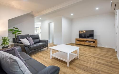 a living room with a couch and a table and a tv at Middleton Beach Holiday Apartment in Albany