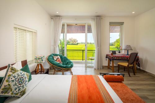 a bedroom with a bed and a desk and a balcony at Greenfield Village Home in Hoi An