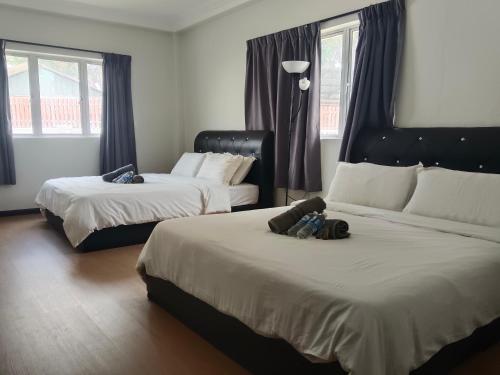a bedroom with two beds and two windows at 69 Hotel in Melaka
