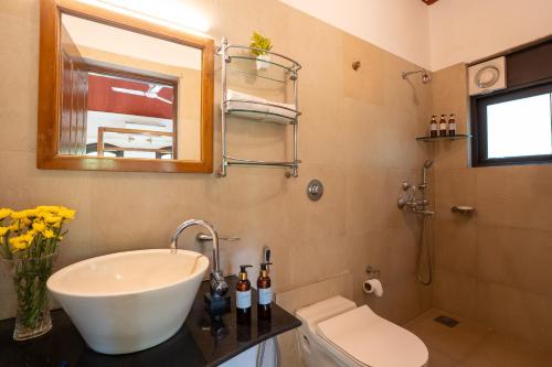 a bathroom with a sink and a toilet and a mirror at Beachside Bliss Villas Candolim 10 min walk from Sinquerim Beach in Sinquerim