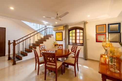 a dining room with a table and chairs and a staircase at Beachside Bliss Villas Candolim 10 min walk from Sinquerim Beach in Sinquerim