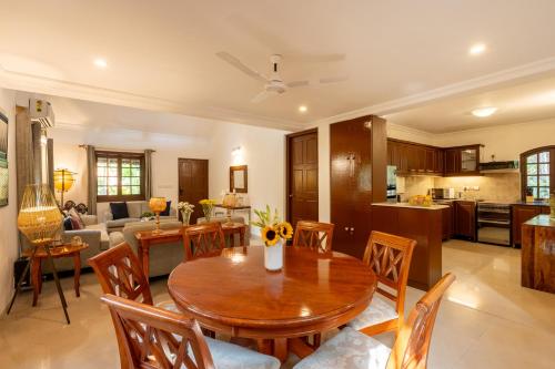 a kitchen and living room with a wooden table and chairs at Beachside Bliss Villas Candolim 10 min walk from Sinquerim Beach in Sinquerim