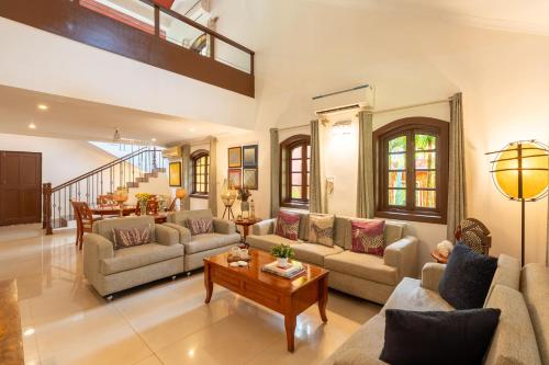 a living room with couches and a table at Beachside Bliss Villas Candolim 10 min walk from Sinquerim Beach in Sinquerim