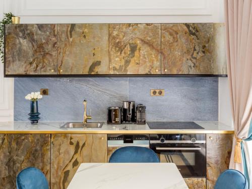 une cuisine avec un évier et un comptoir avec des chaises bleues dans l'établissement Merveil - Luxury Suite -Champs Elysees-Haussmann I, à Paris