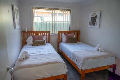 two twin beds in a room with a window at Mudgee House in Mudgee