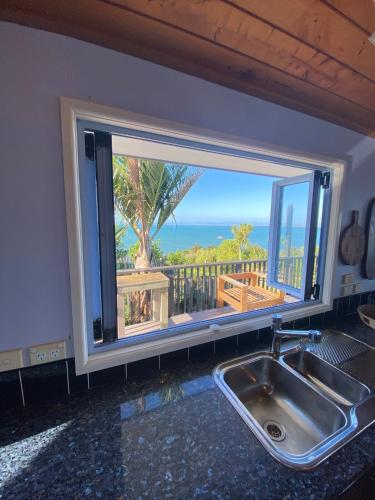 a kitchen sink with a window with a view of the ocean at Viewpoint 8 in Karikari Peninsula
