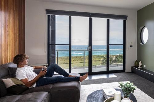 a man sitting on a couch looking out at the ocean at house by the sea in Warrnambool