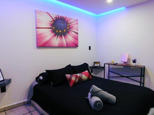 a bedroom with a black bed with a painting on the wall at Depa privado Estadio GNP -Foro Sol-, Palacio de los Deportes in Mexico City