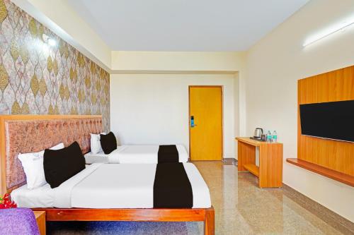 a hotel room with two beds and a flat screen tv at Super Townhouse Oak Electronic City Formerly Hotel Trubell in Bengaluru