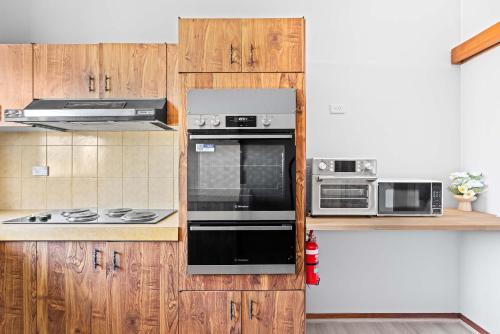 シドニーにあるComfortable Single Room in Convenient Belmore Location - Shared Bathroomの木製のキャビネットと黒い家電製品を備えたキッチン