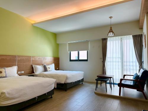 a hotel room with two beds and a chair at Slowly inn in Hengchun
