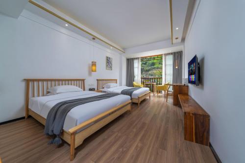 a bedroom with two beds and a table and chairs at Phoenix Mandu River View Homestay in Fenghuang