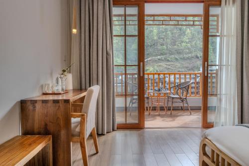 a room with a bed and a desk and a balcony at Phoenix Mandu River View Homestay in Fenghuang