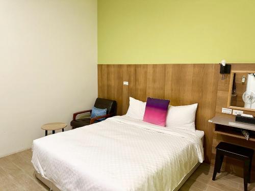 a bedroom with a white bed with a purple pillow at Slowly inn in Hengchun