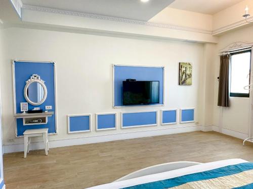 a room with blue and white walls and a flat screen tv at Slowly inn in Hengchun