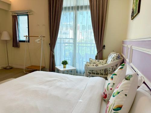 a bedroom with a bed and a chair and a window at Slowly inn in Hengchun