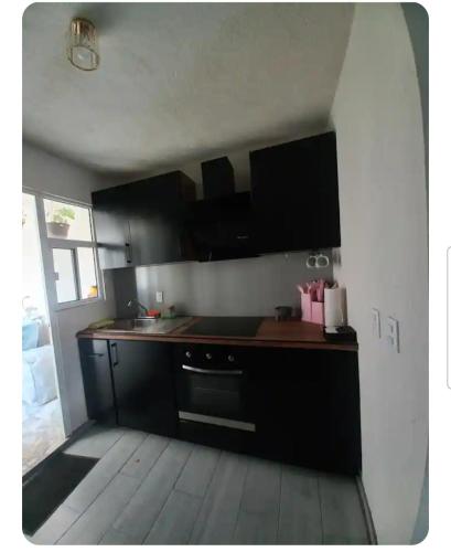 a kitchen with black cabinets and a wooden floor at Departamento Confortable Fracc los Sauces in Zapotiltic