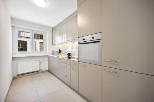 a white kitchen with white cabinets and a window at UP&GREAT Apartments - Stylish City Living in Zürich