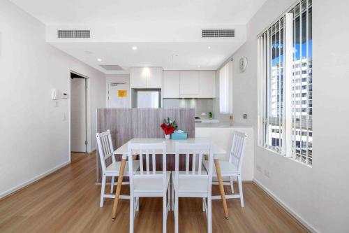 a kitchen and dining room with a white table and chairs at Modern 2BR Apartment in Sydney