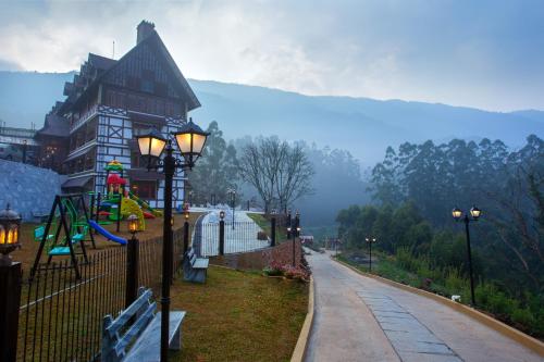 a building with a playground in front of a river at Koviloor Resort in Vattavada