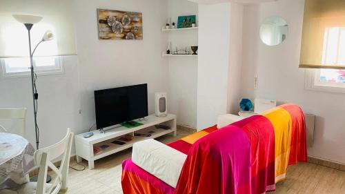 カディスにあるÁtico Cádiz Playaのカラフルなシーツが敷かれたベッドとテレビのある部屋