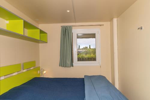 a bedroom with a blue bed and a window at Agriturismo Nonna Stella in Bibbona