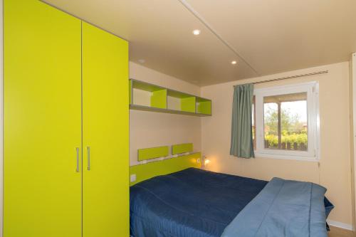 a bedroom with a blue bed and a yellow cabinet at Agriturismo Nonna Stella in Bibbona