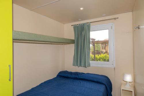 a bedroom with a blue bed and a window at Agriturismo Nonna Stella in Bibbona