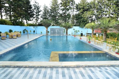 a pool at a resort with chairs and trees at Aroma Green Farm Manesar with Pool in Bahora