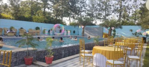 a pool with tables and chairs and a fountain at Aroma Green Farm Manesar with Pool in Bahora
