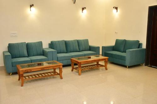 a waiting room with blue couches and coffee tables at Aroma Green Farm Manesar with Pool in Bahora