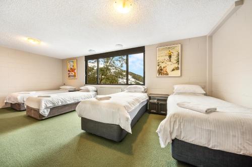 een kamer met 3 bedden en een groot raam bij Pontresina 1 in Falls Creek