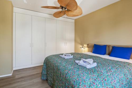 a bedroom with a bed with blue pillows and a ceiling fan at UP&GREAT Apartments - Stylish City Living in Zürich