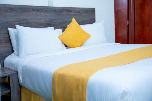 a bedroom with a large white bed with a yellow pillow at KISIMANI ECO RESORT & SPA LTD in Isiolo