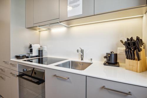 a kitchen with white cabinets and a sink at UP&GREAT Apartments - Stylish City Living in Zürich