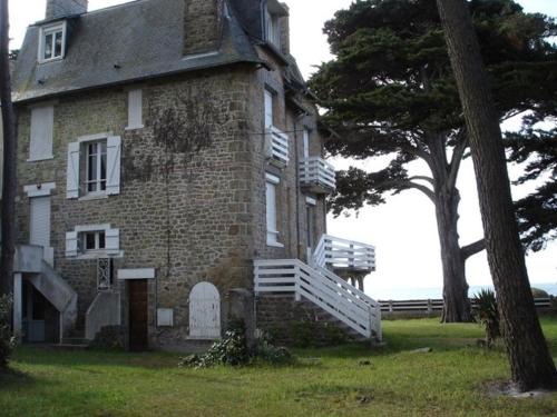 une vieille maison en briques avec un arbre devant elle dans l'établissement Sea View Apartment, à Carnac