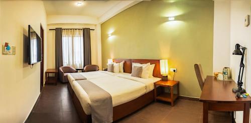 a hotel room with a large bed and a desk at Morven Hotel Colombo in Colombo