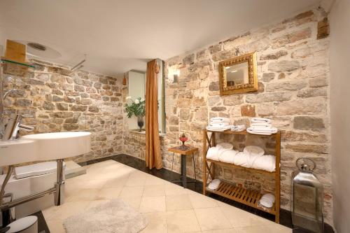 a bathroom with a sink and a stone wall at Palazo dei CONTI in Split Centre OLD town in Split
