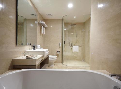 a bathroom with a tub and a sink and a toilet at Platinum Hotel Jimbaran Beach Bali in Jimbaran