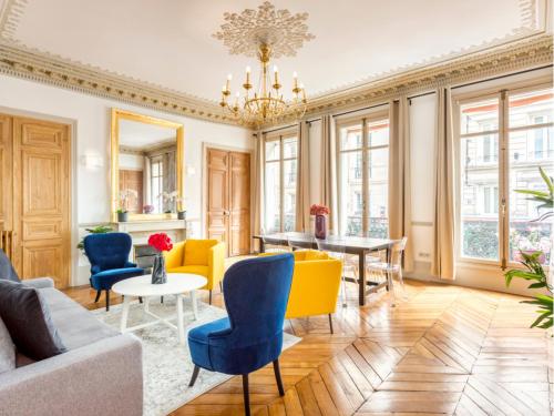 un salon avec des chaises jaunes et bleues et une table dans l'établissement Merveil - Family Suite - Opera - Castellane, à Paris