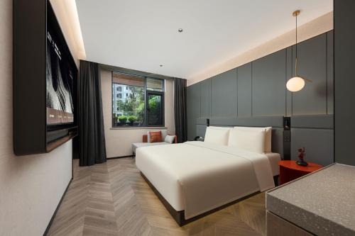 成都市にあるAtour S Hotel Chengdu Huaxi Provincial Stadium Metro Stationの白いベッドとテレビのある寝室