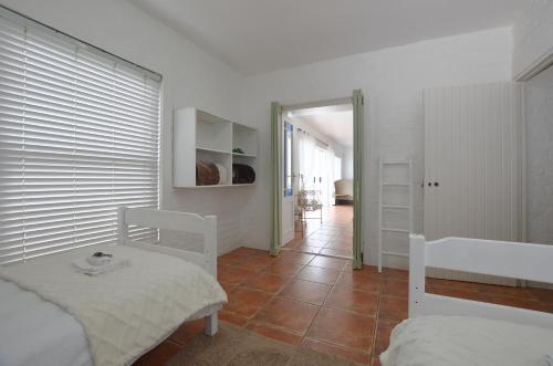 a bedroom with two beds and a hallway with a door at Urban Sole Beach House in Yzerfontein