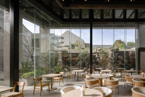 Un restaurante con mesas y sillas y grandes ventanales. en 扬州广陵有熊酒店, en Yangzhou