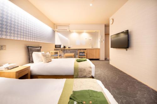 a hotel room with two beds and a flat screen tv at Hotel Naranohamori in Nara