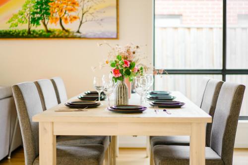 a table with chairs and a vase of flowers on it at New family-friendly home in Melton South