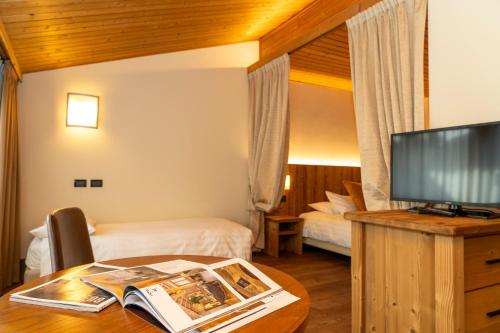 a hotel room with two beds and a table with a tv at Palace Hotel Wellness & Beauty in Bormio