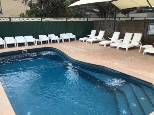 a swimming pool with white chairs and a row of chairs at Dylene Holiday Park in Portarlington