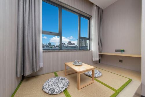 a living room with a table and a large window at Echarm Hotel Foshan Guangfo Road Jiaokou Metro Station in Foshan