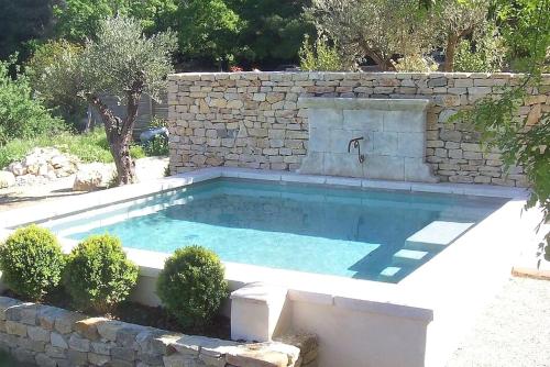 une piscine avec une fontaine dans un mur en pierre dans l'établissement Le Bastidon des Collines, à Aubagne